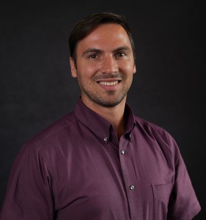 Adam Farley, Licensed Hearing Instrument Specialist, smiling in a burgundy button-down shirt